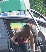 Busty girl leans inside car