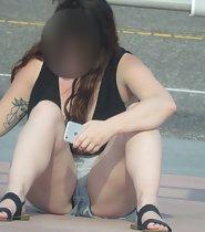 Tattooed girl spreads legs in shorts