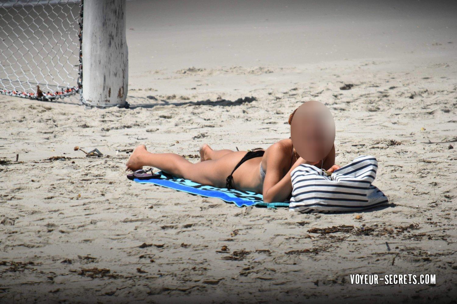 Redhead fixes bikini top on beach - Voyeur Videos