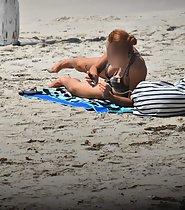 Redhead fixes bikini top on beach - Voyeur Videos