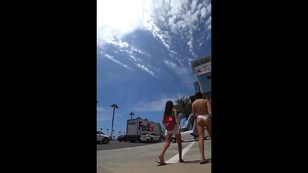 Tall girl in white thong bikini walks through street Foto