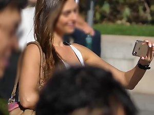 Beautiful brunette makes selfies in crowded street Picture 8