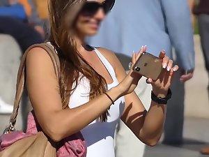 Beautiful brunette makes selfies in crowded street
