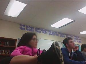 Geeky girl sits with legs on school desk