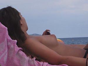 Topless girl texts and sunbathes Picture 8