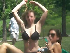 Busty girl suntans in her bra at the park