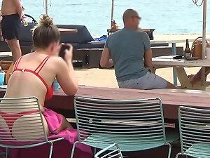 Bubble butt in red bikini is visible through the chair on the beach Picture 2