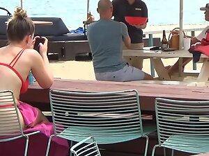 Bubble butt in red bikini is visible through the chair on the beach