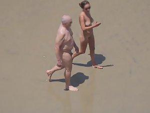 Zooming on weird nudist couple on beach