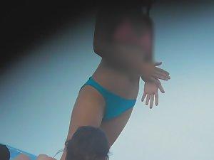 Asian teen girl bends over on beach Picture 1