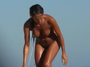 Wet nudist girl gets a hug on the beach