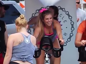 Happy busty girl during group cycling workout