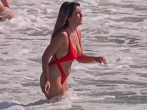 Hottie in sexy red bikini enters the water for a swim