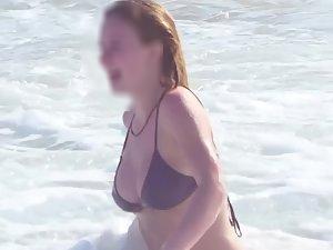 Busty ginger girl enjoys big waves in the water