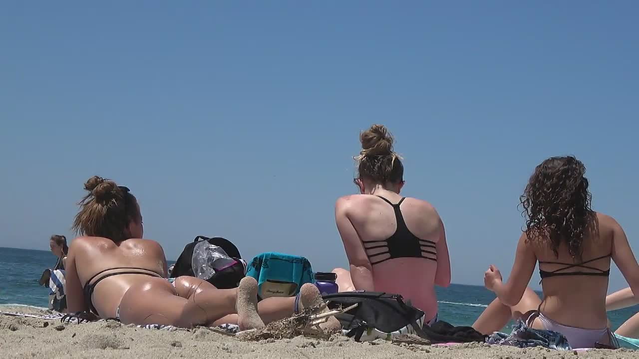Teens bending over in front of me on beach
