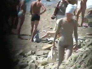 Muddy naked girl on a crowded beach