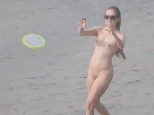 Sporty nudist girl plays frisbee on the beach