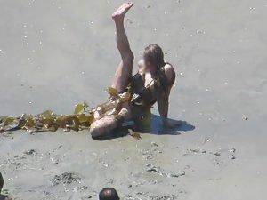 Wacky nudist woman rolls in the mud