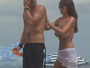 Topless milf gives back rub on beach Picture 7